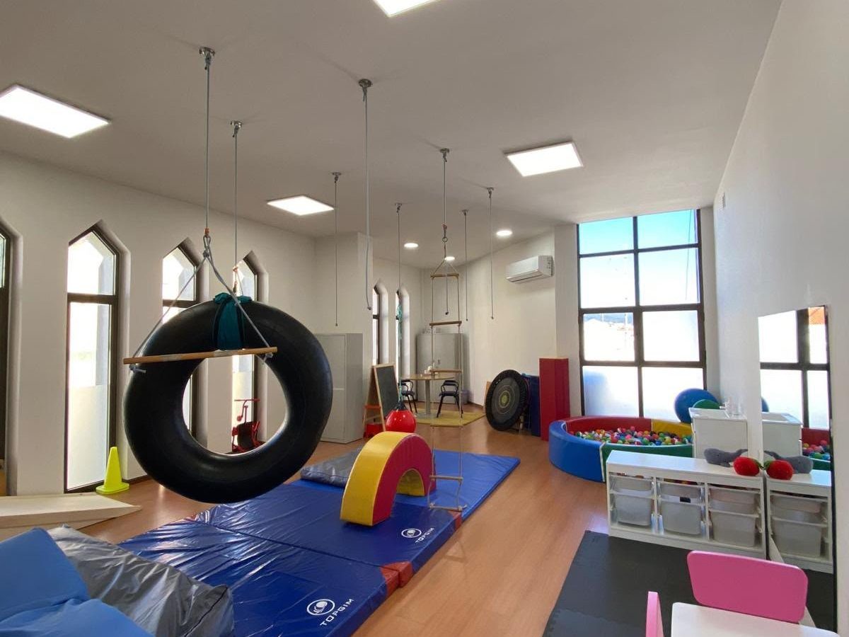 Sala de integração sensorial do MaisPessoa com baloiço de pneu, colchões e mesa para crianças