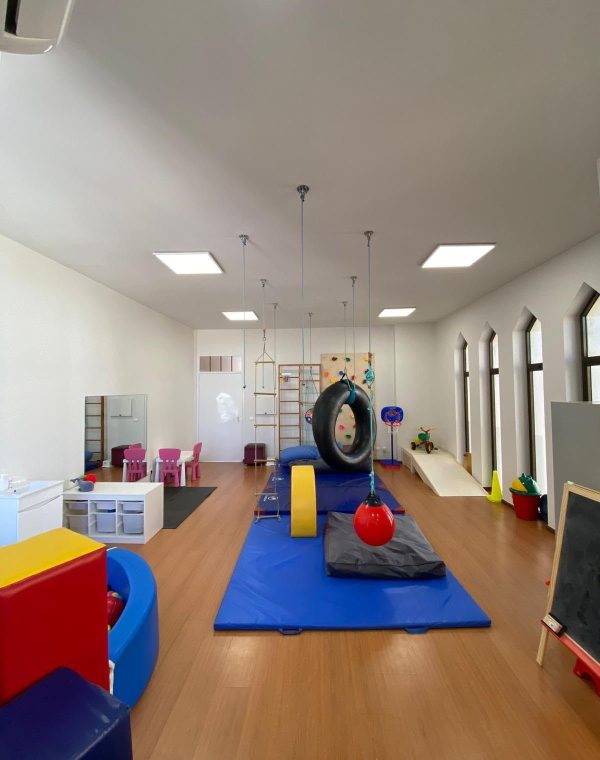 Vista geral da sala de integração sensorial, com baloiços, colchões e espaldar